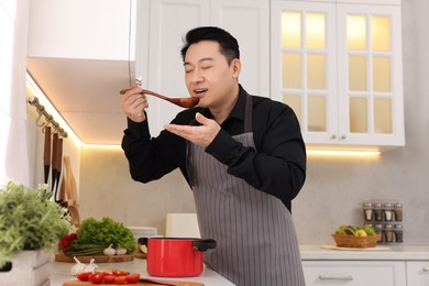 Photo of Man tasting dish after cooking in kitchen