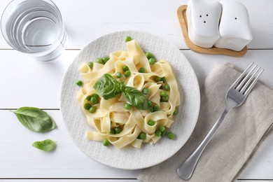 Photo of Delicious pasta with green peas served on white wooden table, flat lay