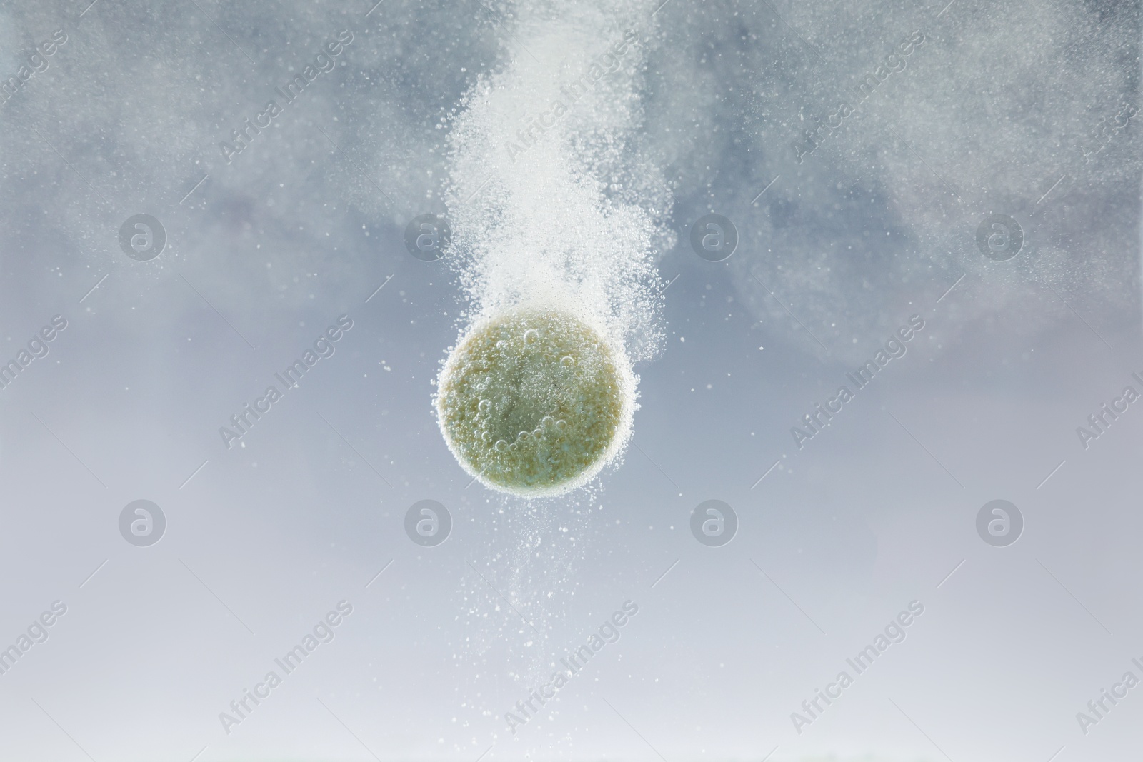 Photo of Effervescent pill dissolving in water on light background, closeup