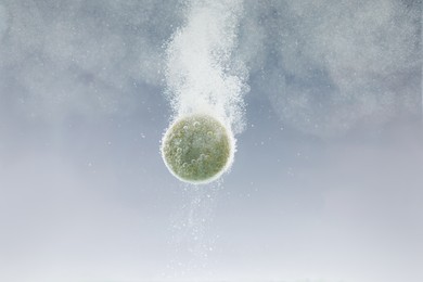 Photo of Effervescent pill dissolving in water on light background, closeup