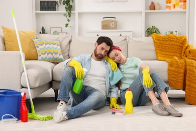 Photo of Spring cleaning. Tired couple with detergents and mop in living room