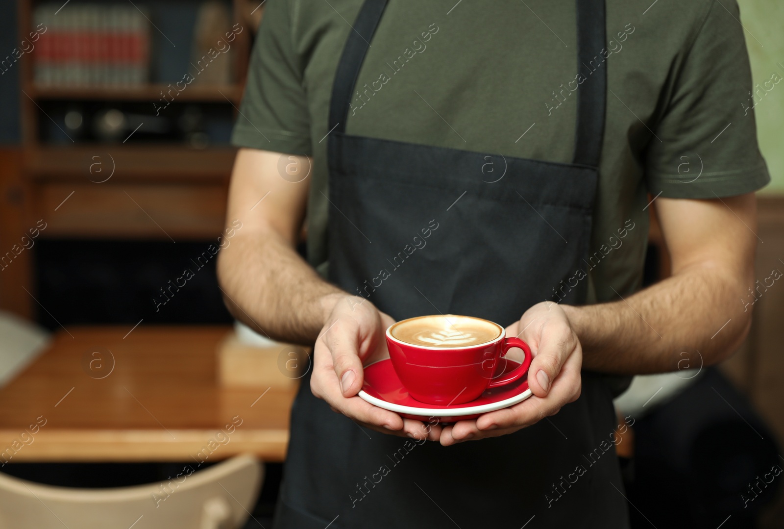 Photo of Barista with cup of coffee in shop, closeup. Space for text