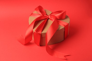Photo of Beautiful heart shaped gift box with bow on red background