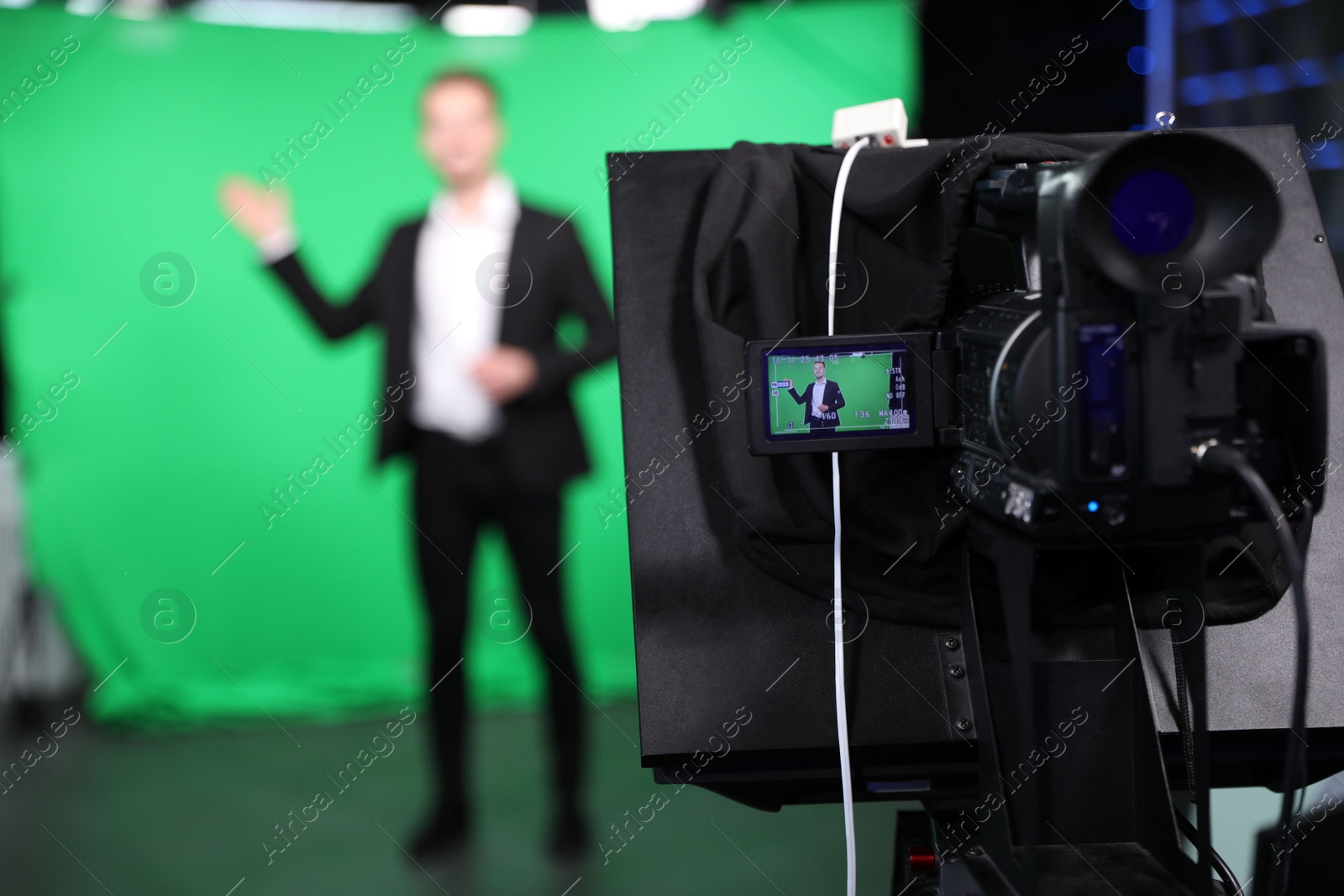 Photo of Presenter working in studio, focus on video camera screen