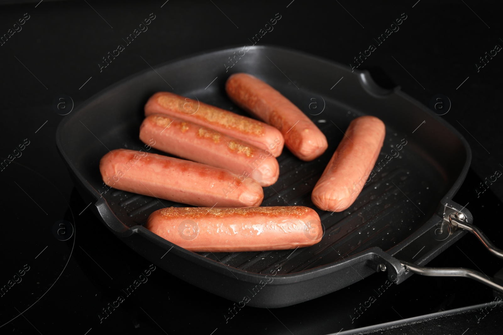 Photo of Cooking vegan sausages in grill pan on cooktop, closeup