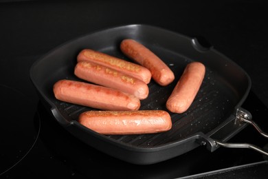 Photo of Cooking vegan sausages in grill pan on cooktop, closeup