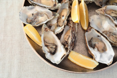 Photo of Fresh oysters with cut juicy lemon on plate, top view