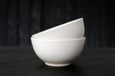 Photo of Stylish empty ceramic bowls on black table. Cooking utensils