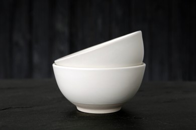 Stylish empty ceramic bowls on black table. Cooking utensils