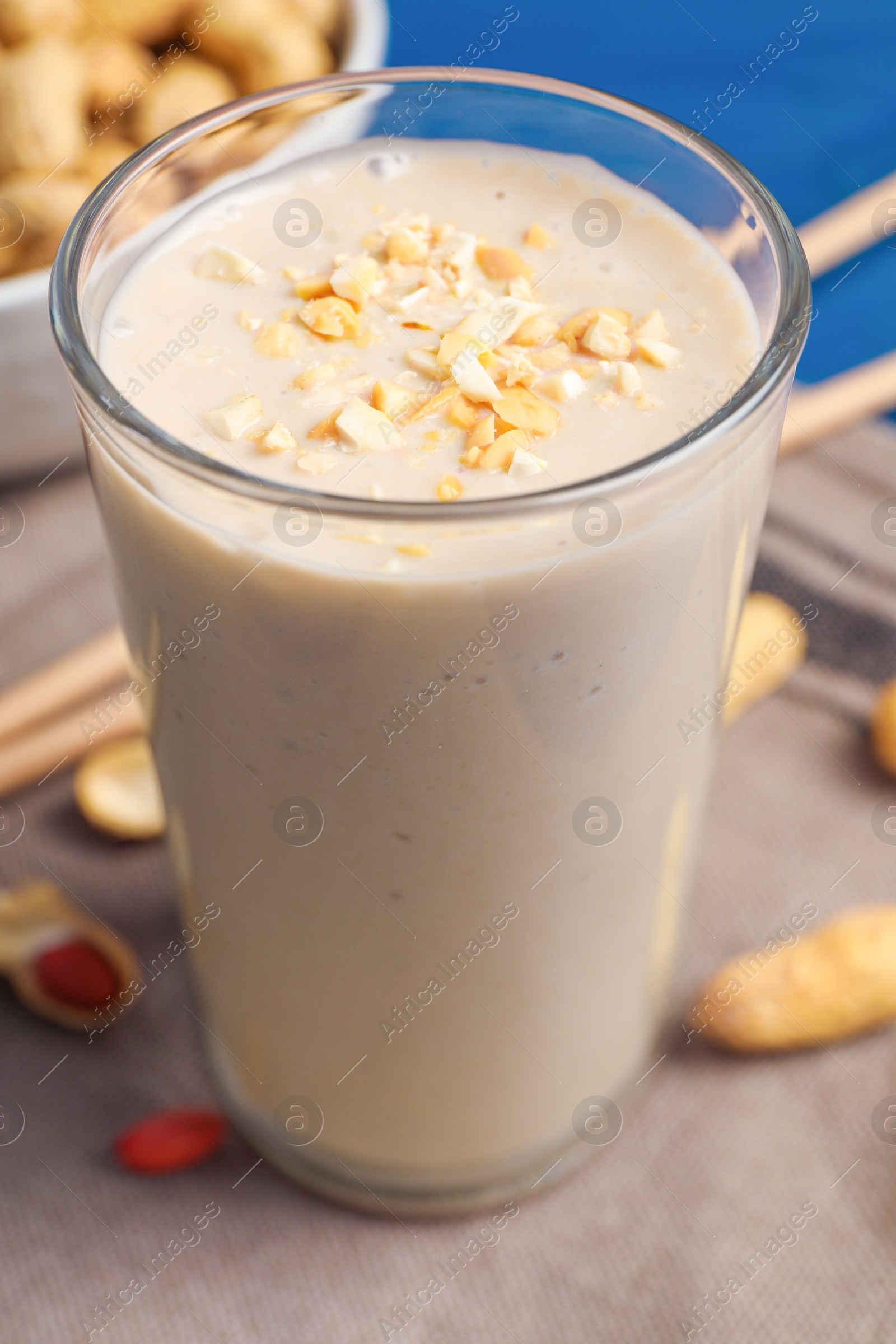 Photo of Glass of tasty banana smoothie with peanuts on table, closeup