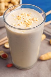 Photo of Glass of tasty banana smoothie with peanuts on table, closeup