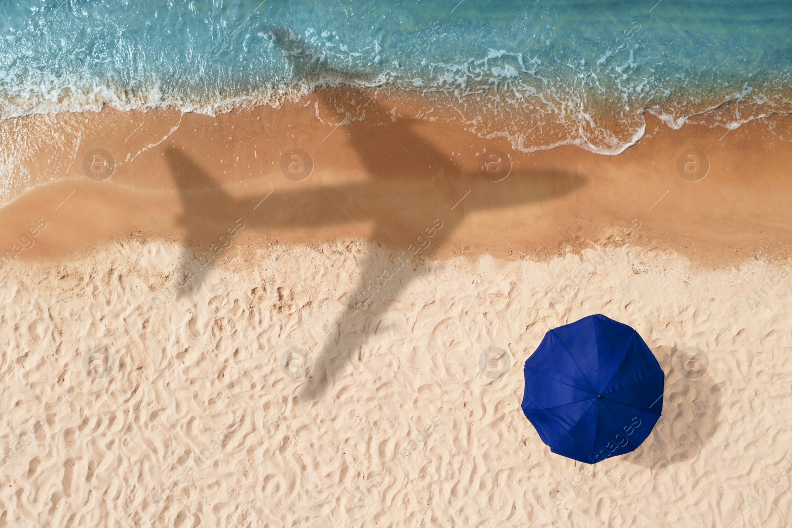 Image of Shadow of airplane above sandy coast, aerial view. Summer vacation