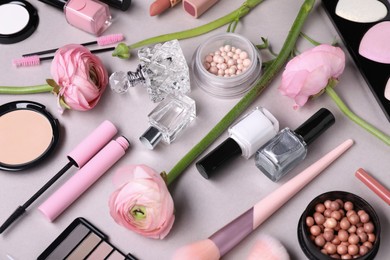 Beautiful spring flowers, different makeup products and perfume on gray background