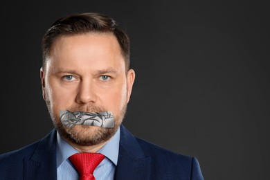 Image of Mature man with taped mouth on grey background. Speech censorship