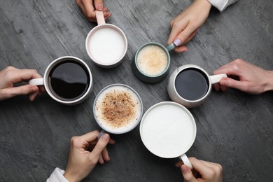Photo of People holding different cups with aromatic hot coffee at grey table, top view