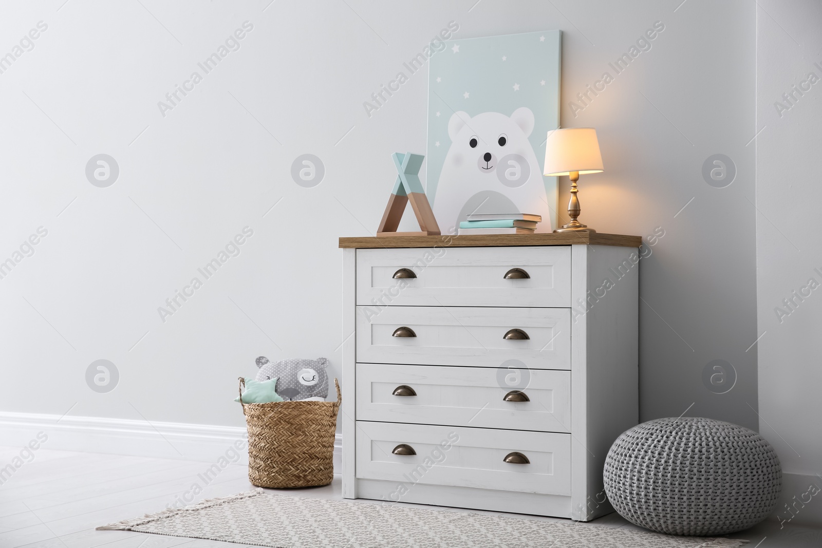 Photo of Modern white chest of drawers near light wall in child room. Interior design