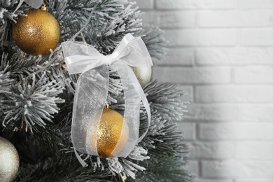 Photo of Decorated Christmas tree near white brick wall, closeup