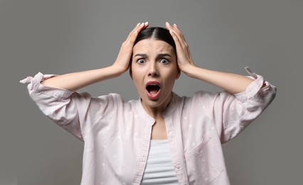 Young woman feeling fear on grey background