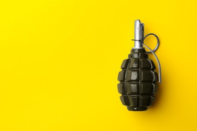 Hand grenade on yellow background, top view. Space for text