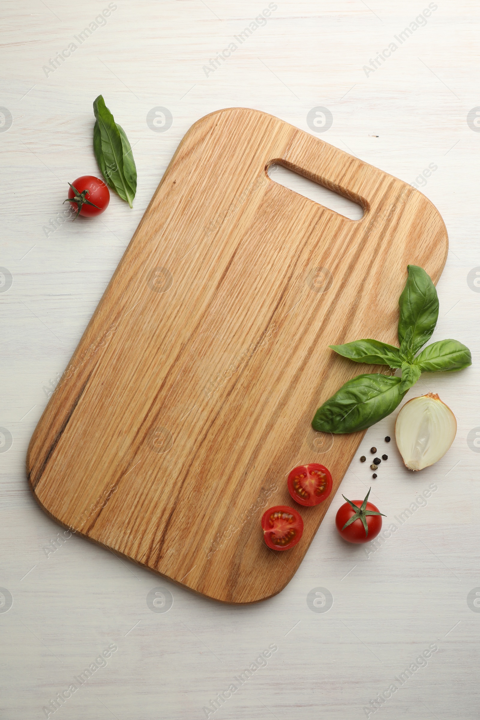 Photo of Cutting board, basil, onion, pepper and tomatoes on white wooden table, flat lay. Space for text