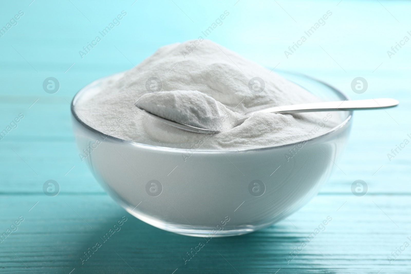 Photo of Baking soda in bowl on blue wooden table