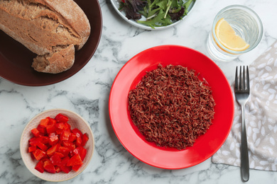 Tasty brown rice served on white marble table, flat lay