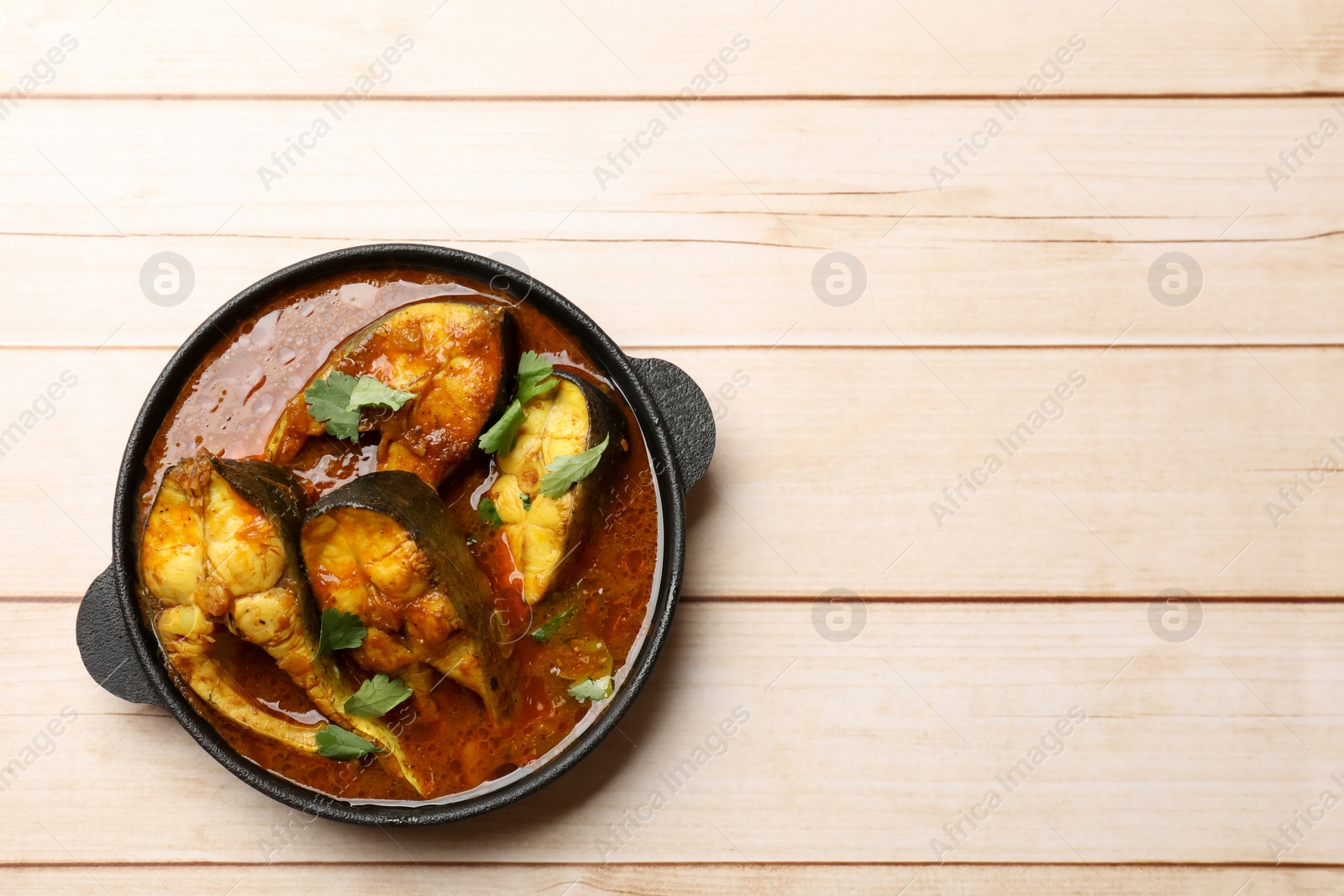 Photo of Tasty fish curry on white wooden table, top view. Space for text. Indian cuisine