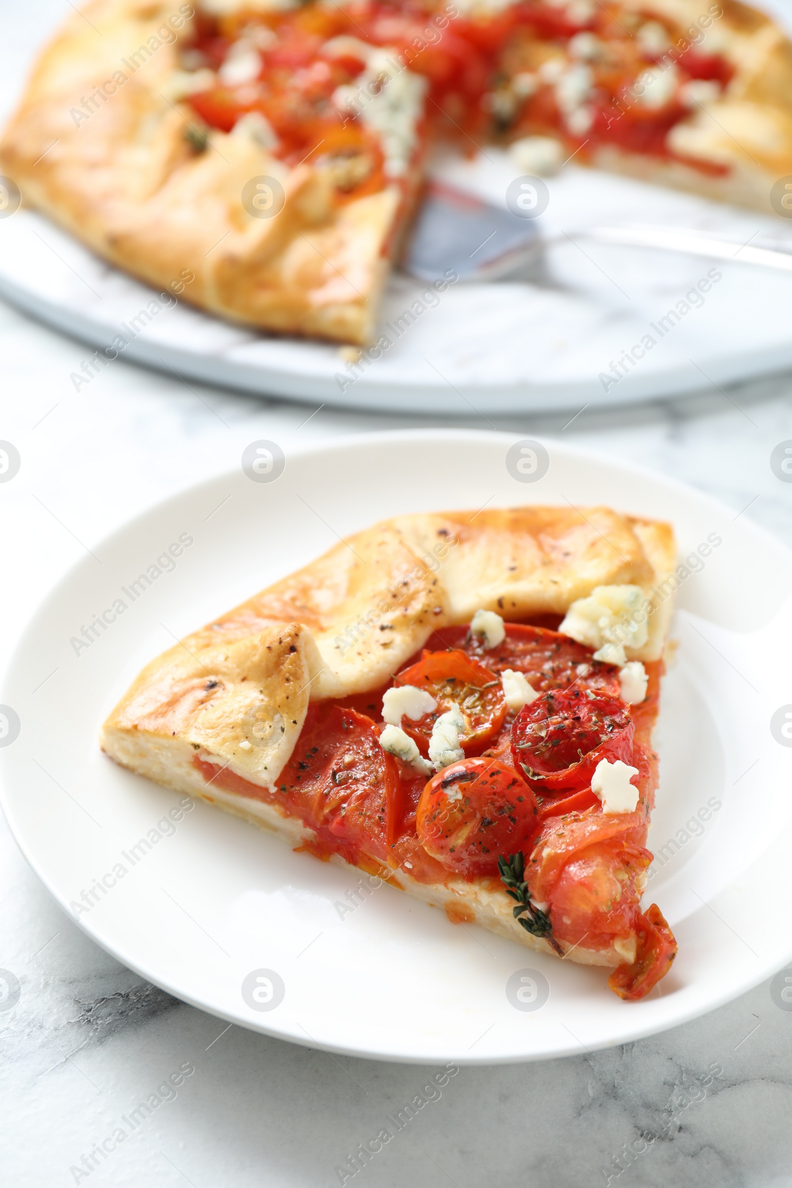 Photo of Tasty galette with tomato and cheese (Caprese galette) on white marble table, closeup