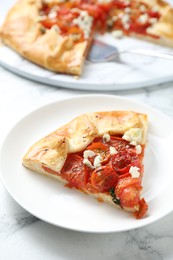 Tasty galette with tomato and cheese (Caprese galette) on white marble table, closeup