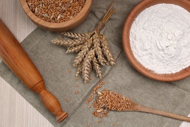 Wheat grains, flour and spikelets on wooden table, flat lay