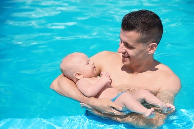 Photo of Man with his little baby in swimming pool on sunny day, outdoors