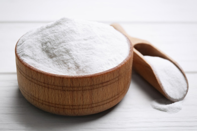 Photo of Baking soda in bowl on white wooden table, closeup