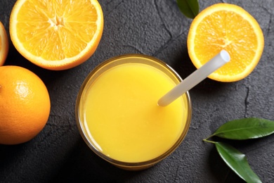 Photo of Glass of orange juice and fresh fruits on grey background, closeup