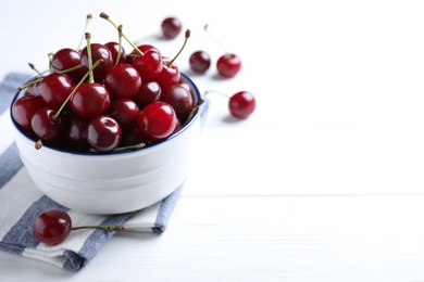 Photo of Sweet juicy cherries on white wooden table. Space for text