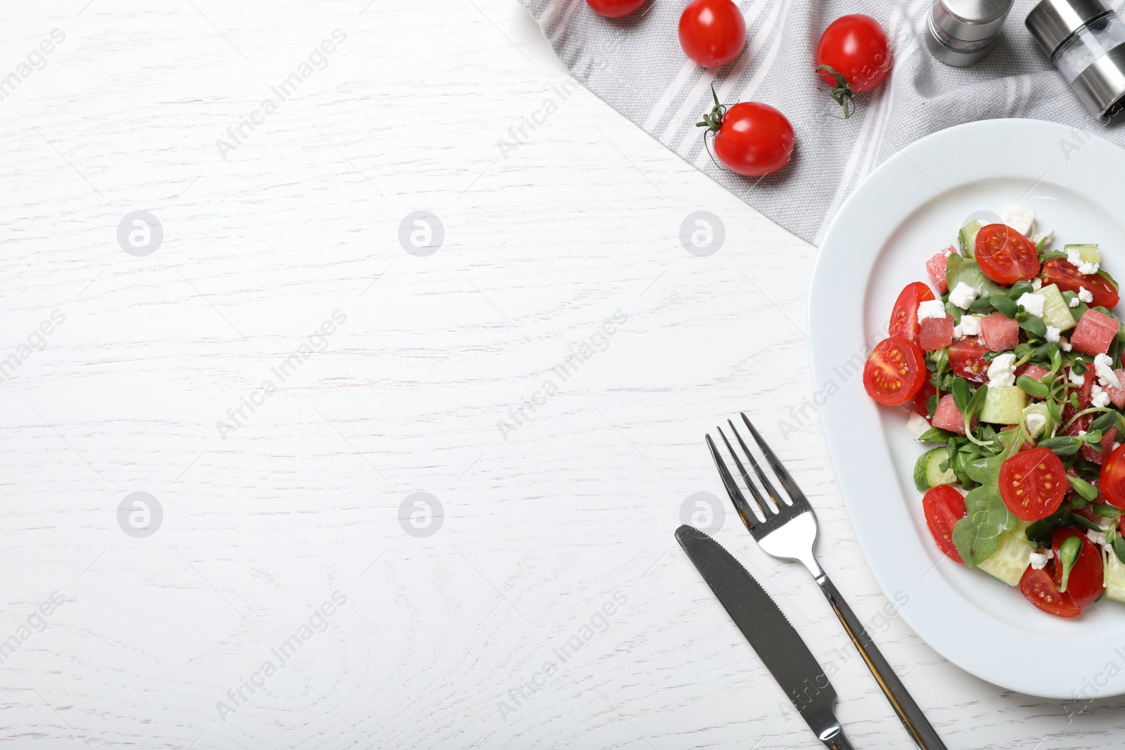 Photo of Delicious salad with watermelon, vegetables and feta cheese served on white wooden table, flat lay. Space for text