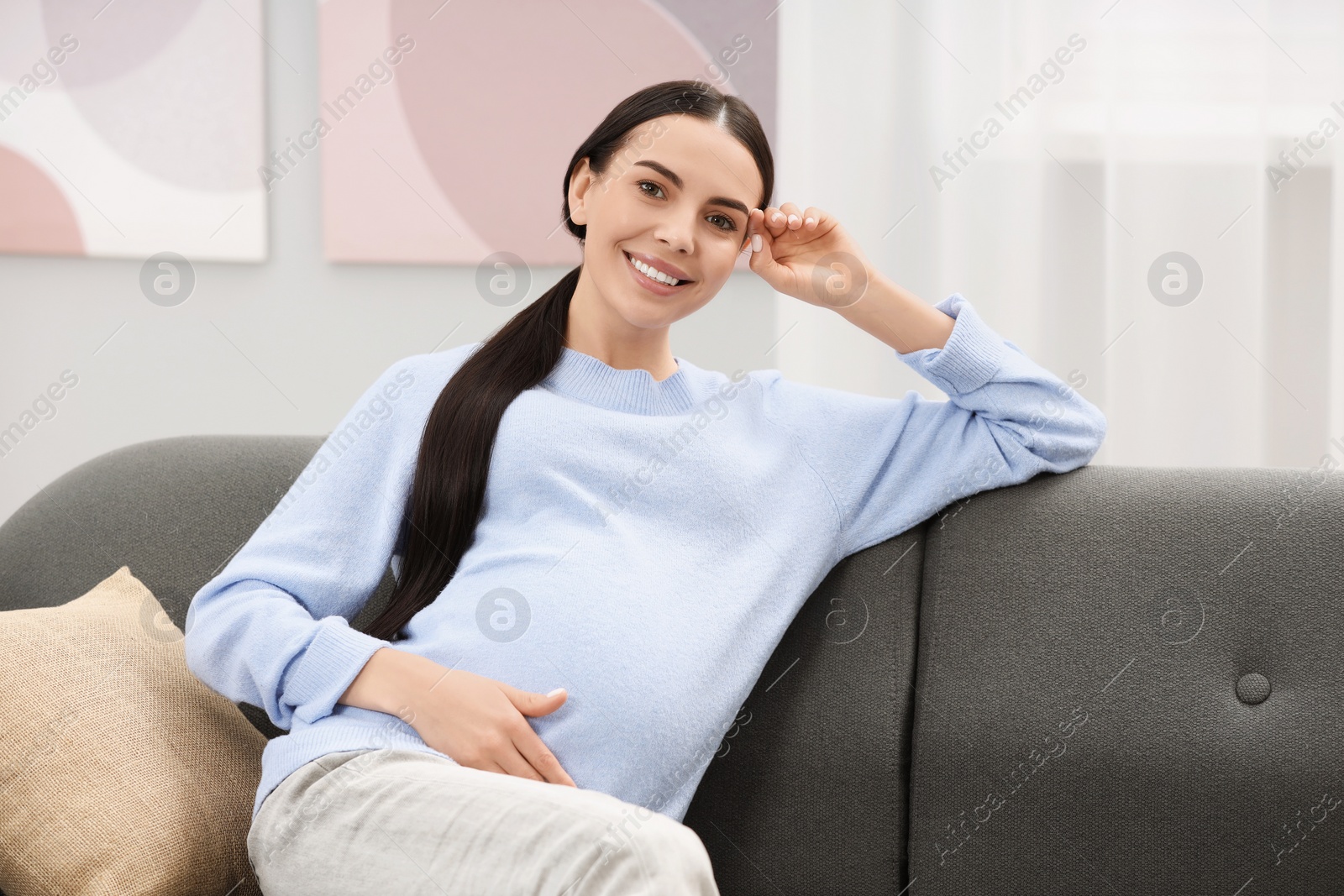 Photo of Happy pregnant woman on sofa at home