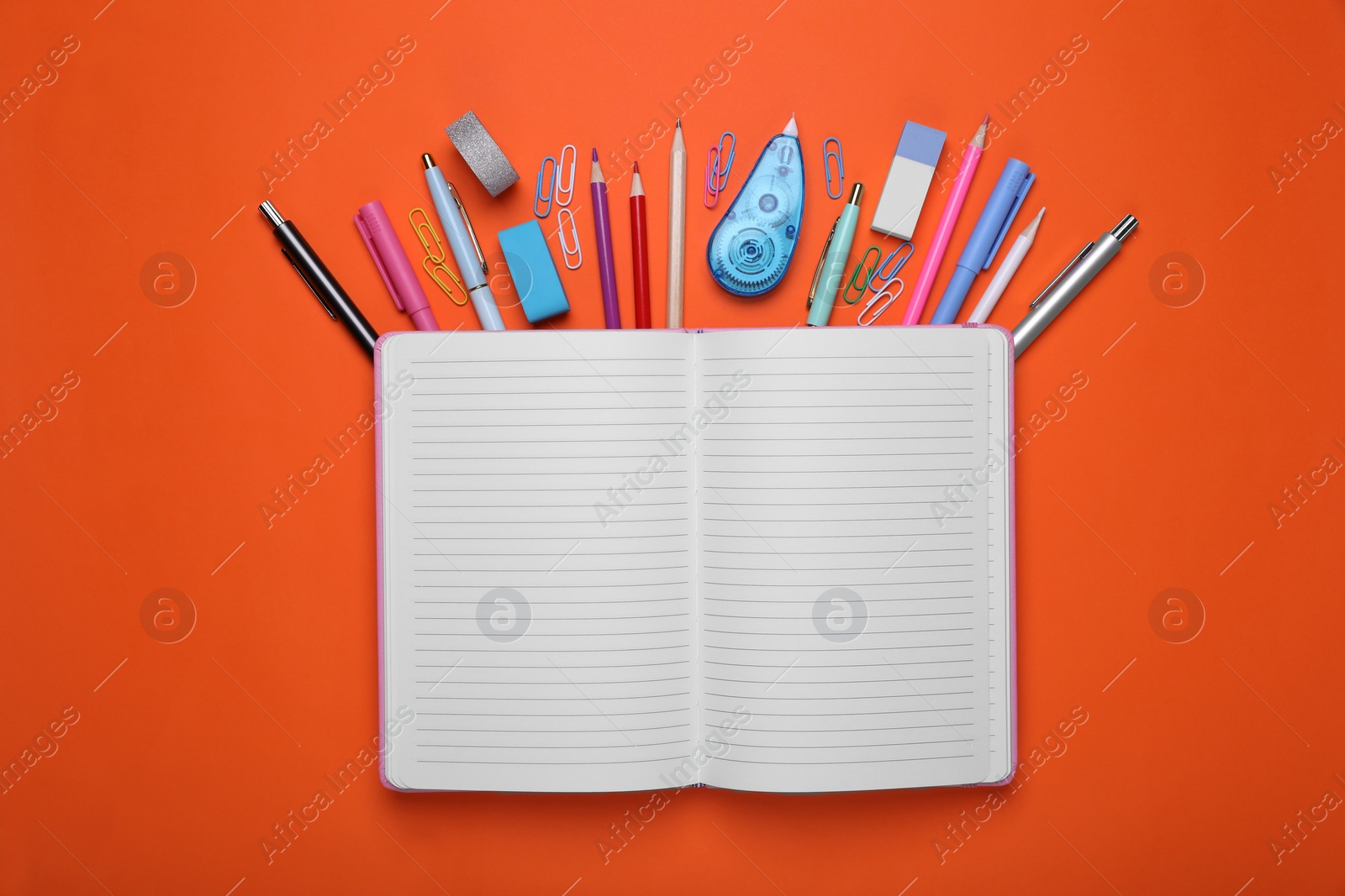 Photo of Flat lay composition with open notebook and other school stationery on red background, space for text. Back to school