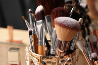 Set of professional brushes and makeup products near mirror on wooden table, closeup