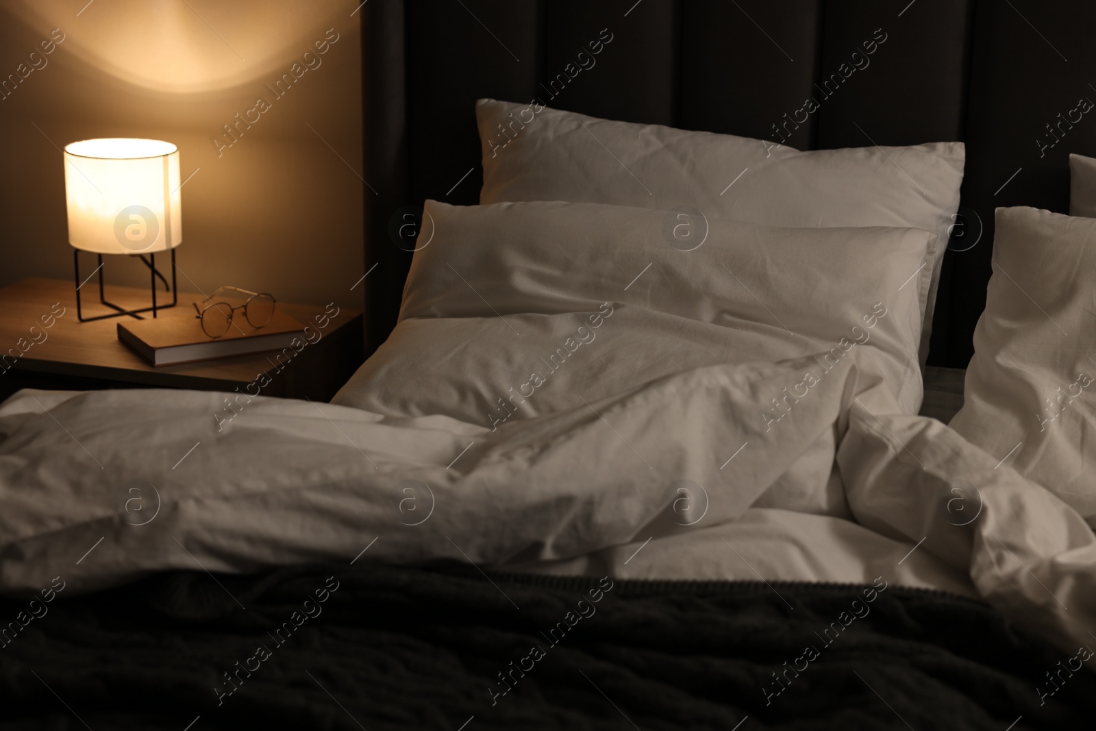 Photo of Soft bed and bedside table with nightlight indoors
