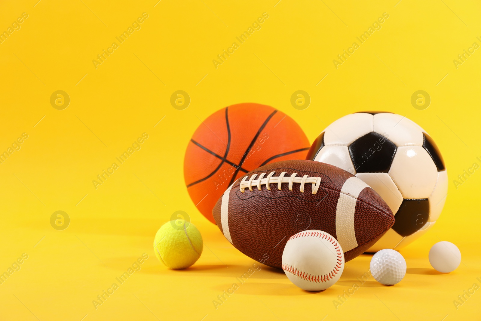 Photo of Many different sports balls on yellow background, space for text