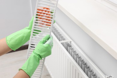 Photo of Woman washing radiator grill with sponge and detergent indoors, closeup. Space for text