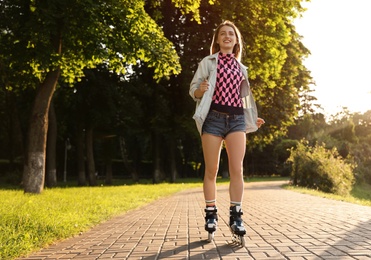 Photo of Beautiful young woman with roller skates having fun outdoors