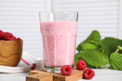 Photo of Tasty raspberry smoothie in glass on white table