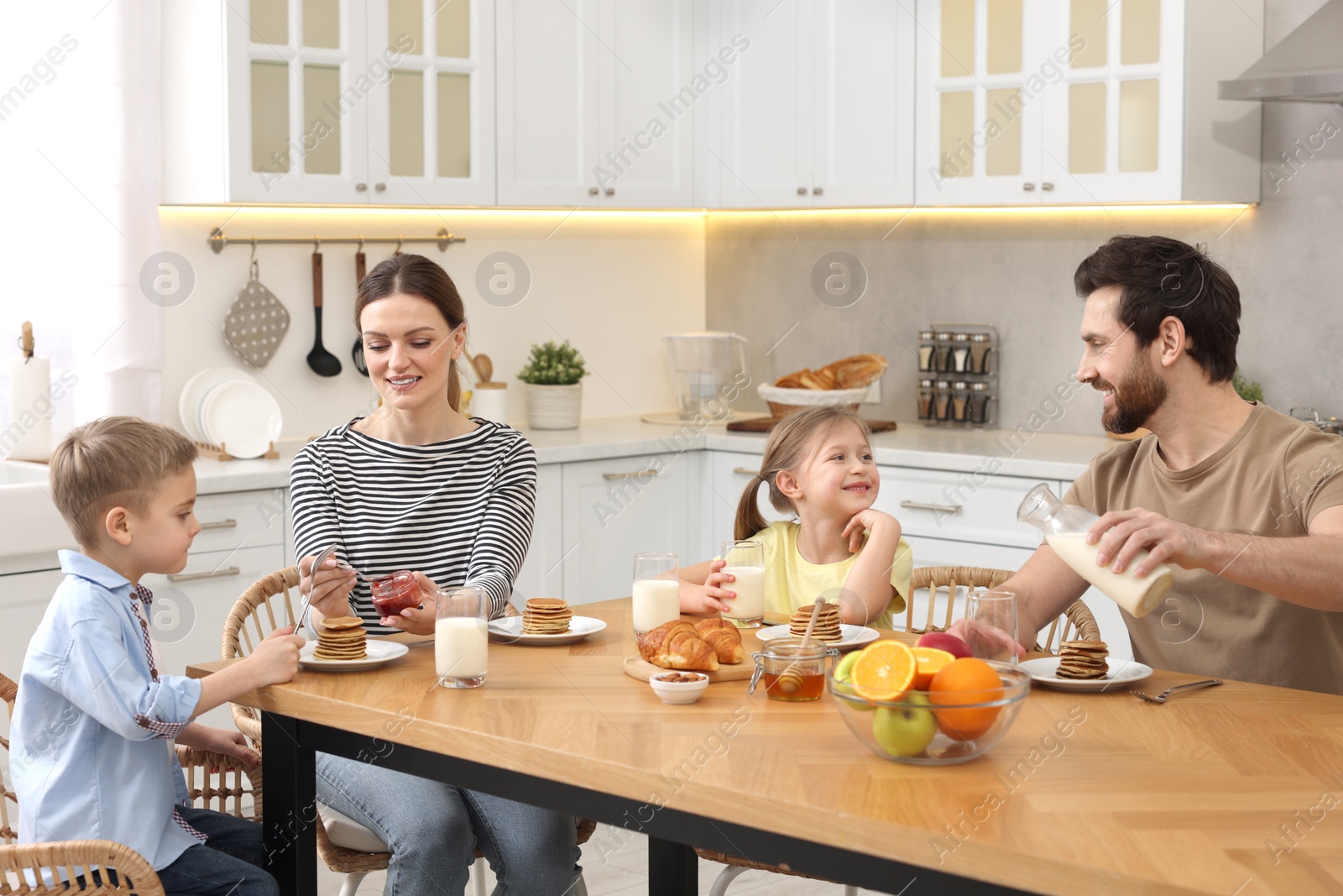 Photo of Happy family having breakfast at table in kitchen