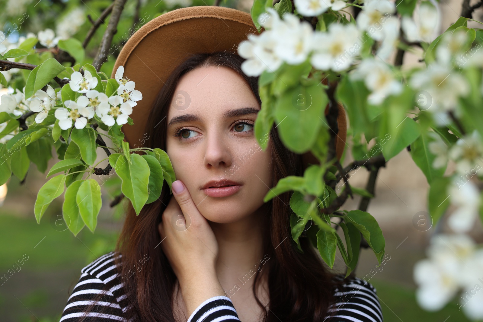 Photo of Beautiful woman in hat near blossoming tree on spring day