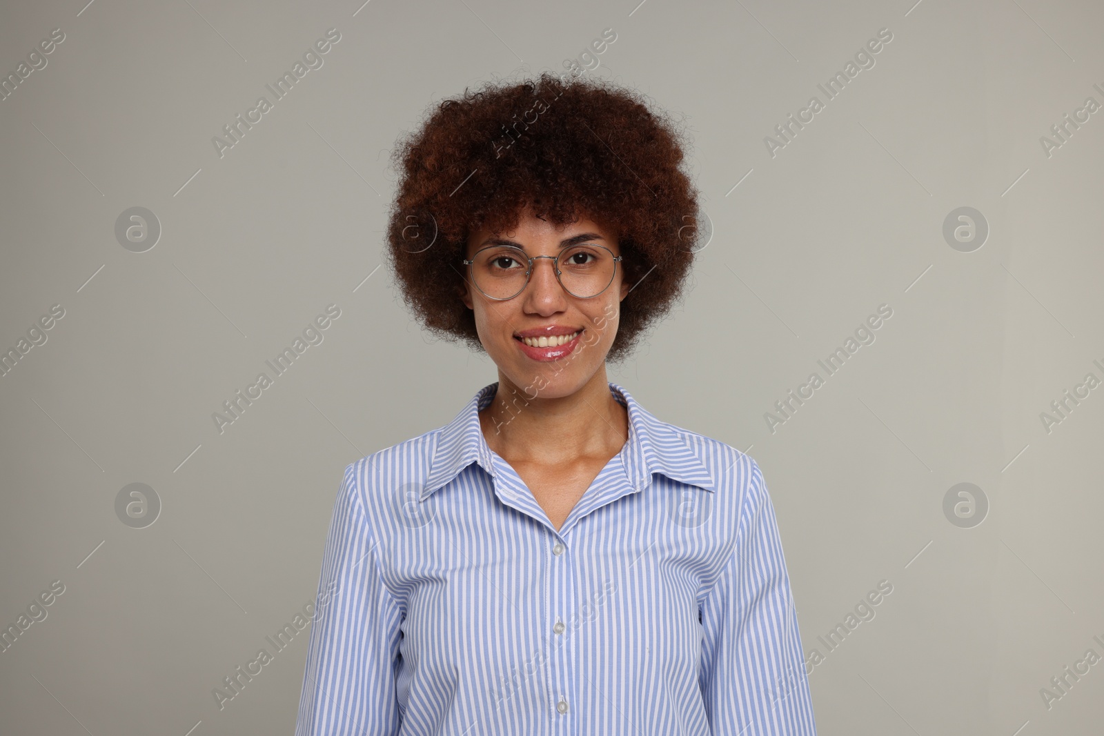 Photo of Portrait of happy young woman in eyeglasses on grey background