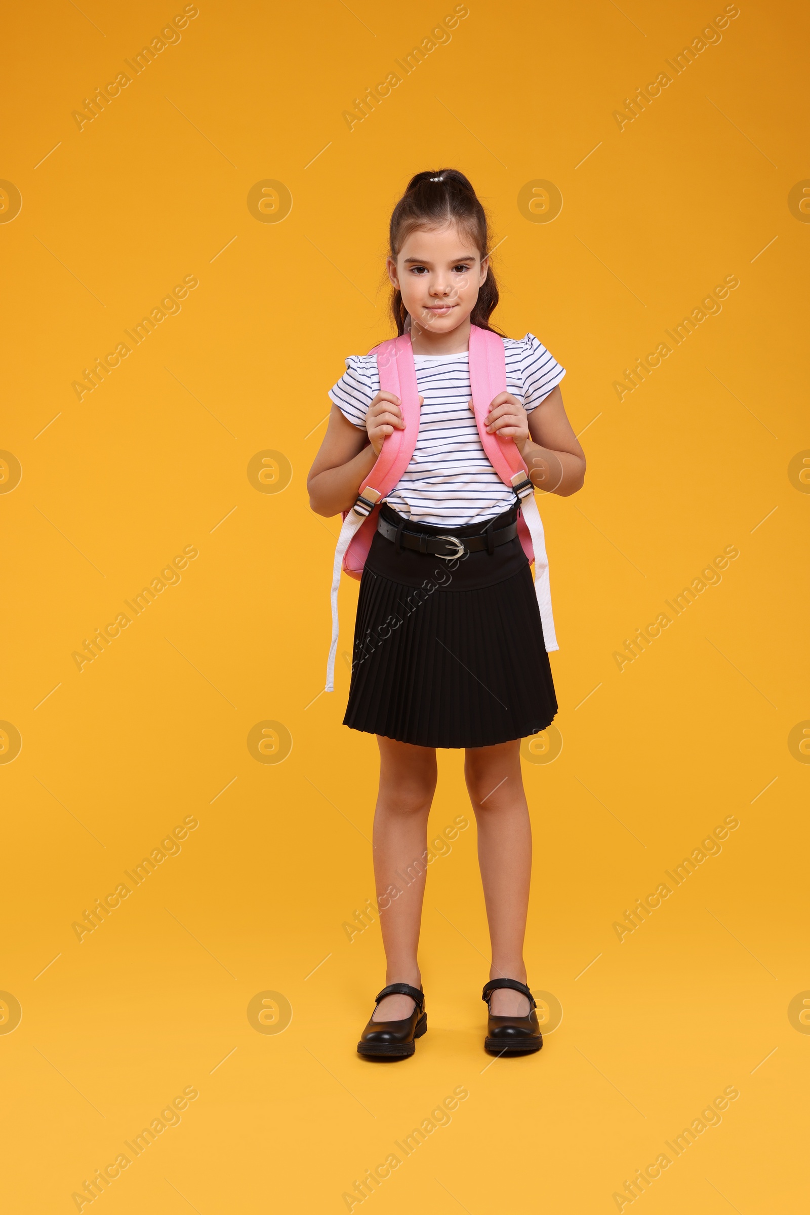 Photo of Back to school. Cute girl with backpack on orange background