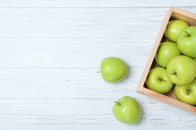 Wooden crate full of fresh green apples on light background, top view. Space for text