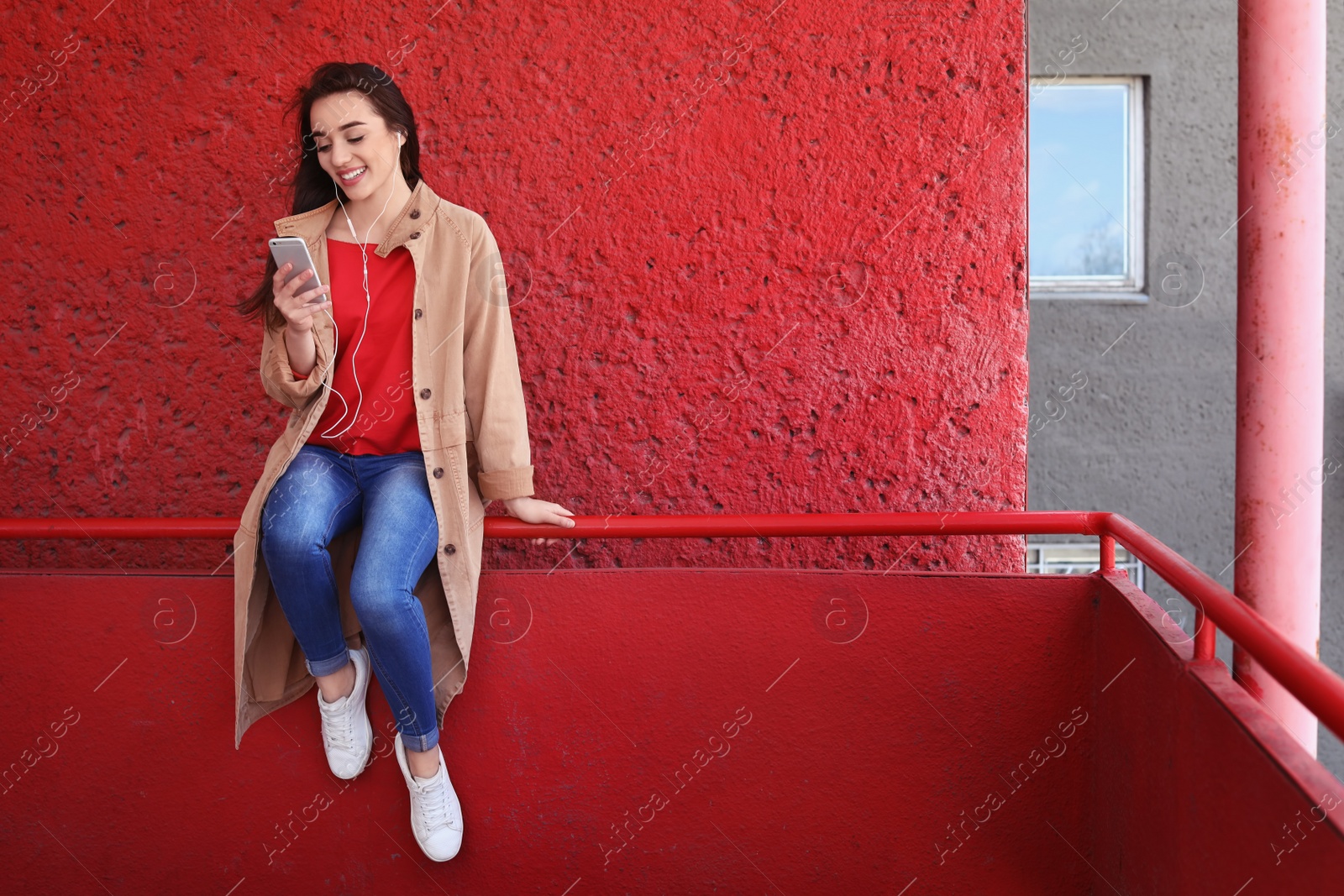 Photo of Young woman using phone for listening to music outdoors