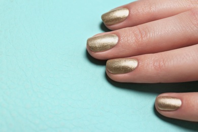 Photo of Woman showing golden manicure on color background, closeup with space for text. Nail polish trends